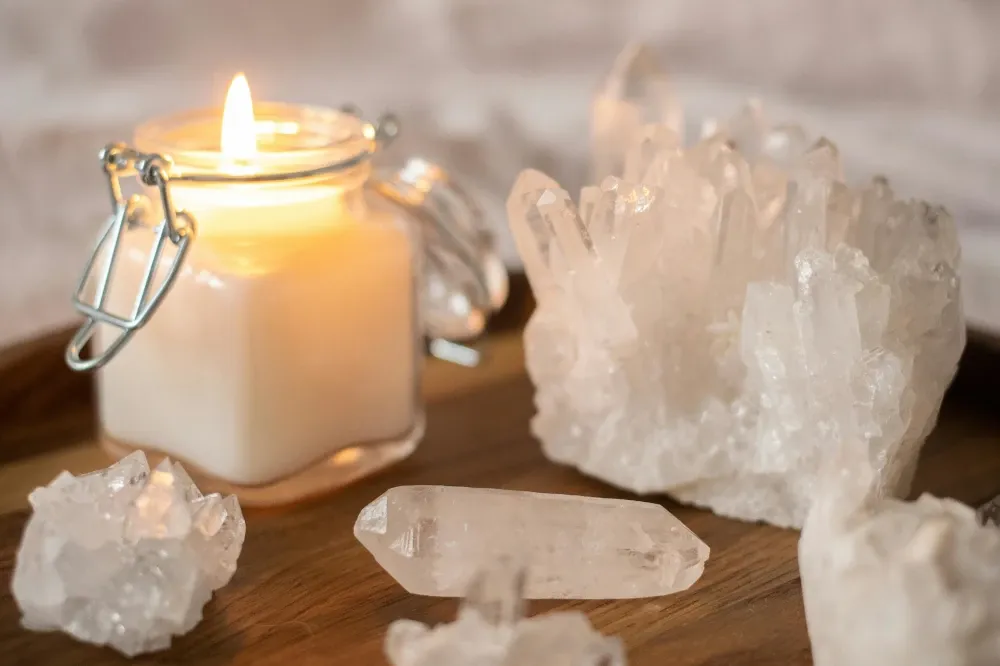 Raw clear quartz crystals on wooden table with lit candle